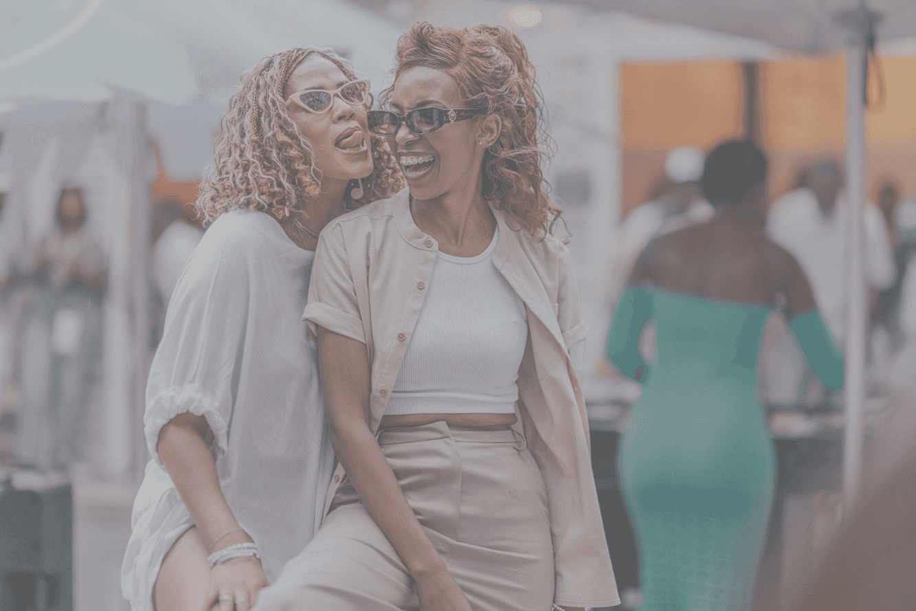 Two people in sunglasses posing together at an outdoor gathering.